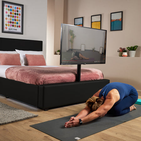 Luxury black TV bed with soft LED lighting, a sleek design and built in TV mount for morning yoga or home exercise sessions.